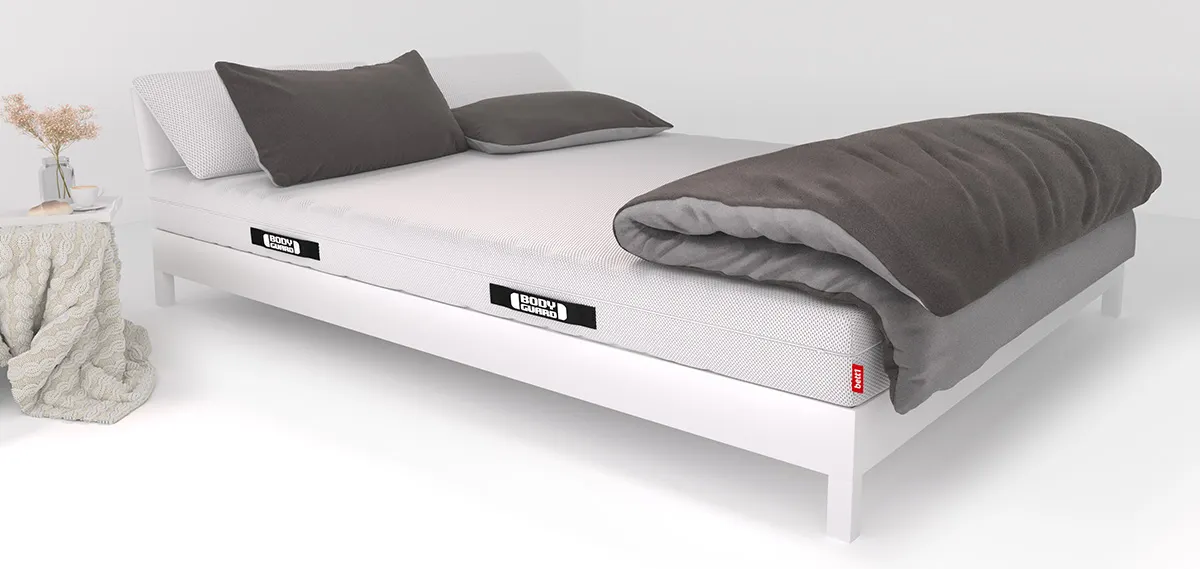 Op een bed liggen twee kussens en een groot dekbed.