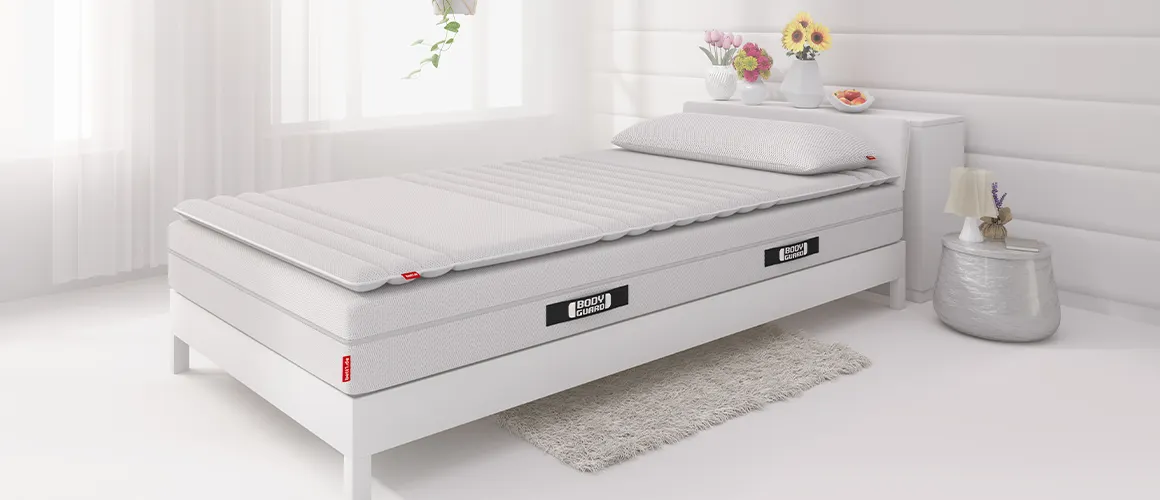 In een lichte slaapkamer staat een bed van 90×200 cm met daarop een matras, een topmatras van 90×200 cm en het Visko-kussen.