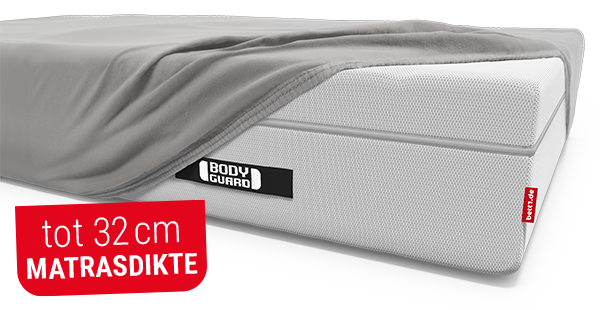 Het BODYGUARD® Boxspring-matras, deels bedekt met het BODYGUARD® extra hoge hoeslaken. Tekst: tot 32 cm matrasdikte