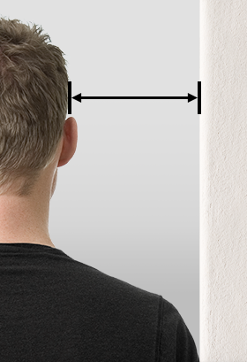 Photo: A person stands with their shoulder to the wall, an arrow is drawn between the wall and their ear.