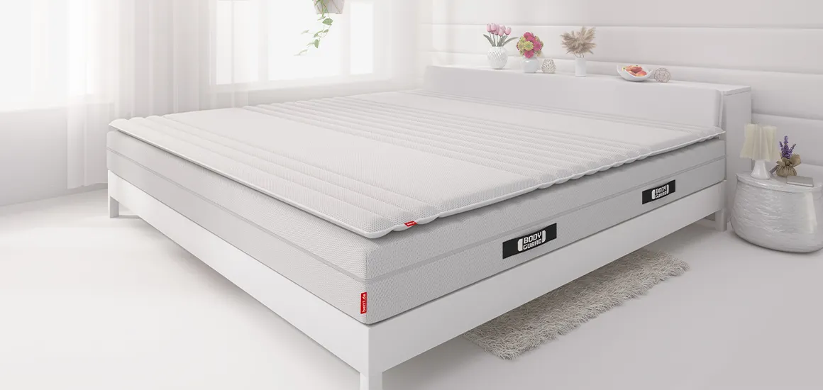 Op een bed liggen het BODYGUARD®-matras met daarop de BODYGUARD®-topmatras.