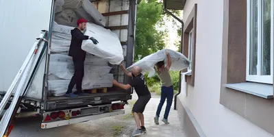 Foto: Drei Personen entladen einen Lkw mit gestapelten BODYGUARD Matratzen.