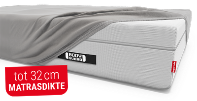 Het BODYGUARD® Boxspring-matras, deels bedekt met het BODYGUARD® extra hoge hoeslaken. Tekst: tot 32 cm matrasdikte
